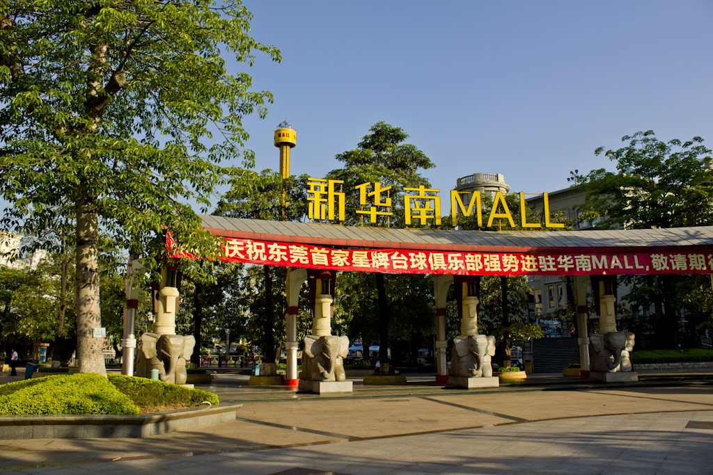 New South China Mall entrance with yellow signage, elephant statues, and red banner under blue sky.