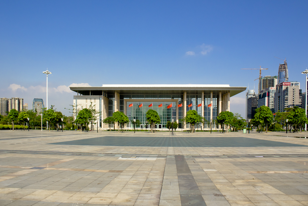 Empty concrete plaza in front of a modern government building with Chinese flags in Dongguan.