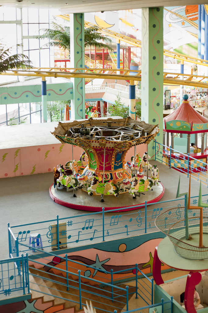 Empty amusement park carousel inside New South China Mall with colorful rides and structures.