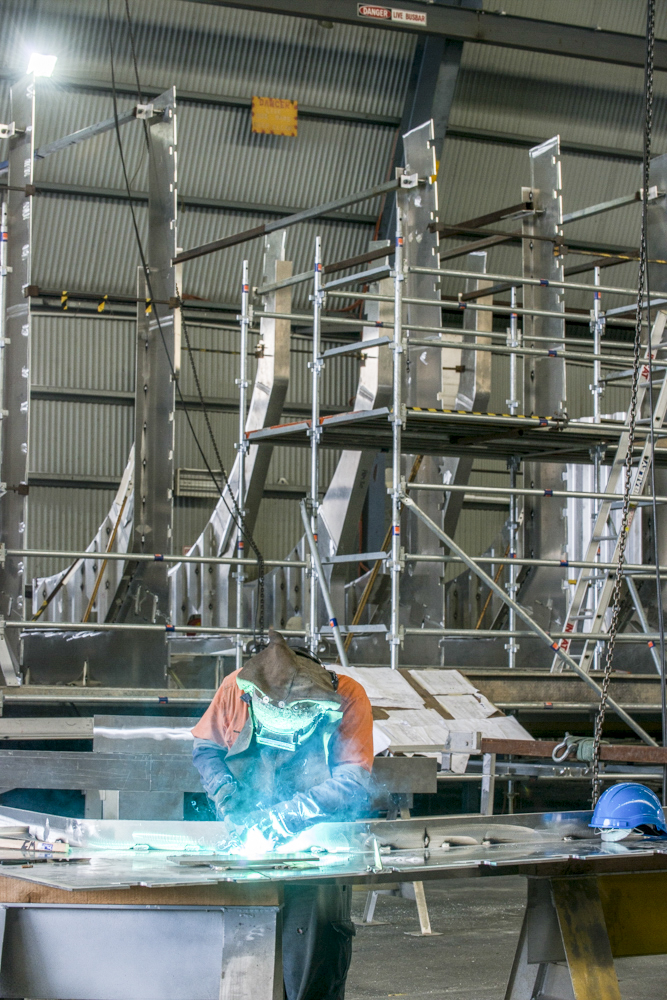 Welder in protective gear working on aluminium hull at Incat shipyard in Hobart.