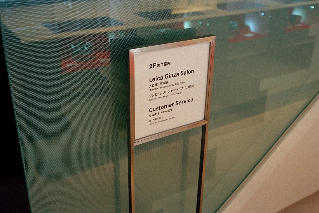 Signage at the Leica Ginza Salon displaying customer service information in Japanese and English.
