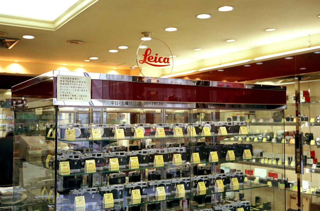 Leica camera display case with vintage cameras and yellow price tags at Katsumido Camera shop in Ginza, Tokyo.