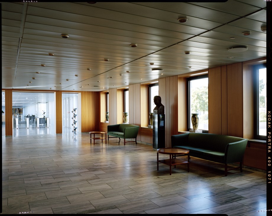 Modernist lobby with wood paneling, green chairs, and skylights at Maersk headquarters.
