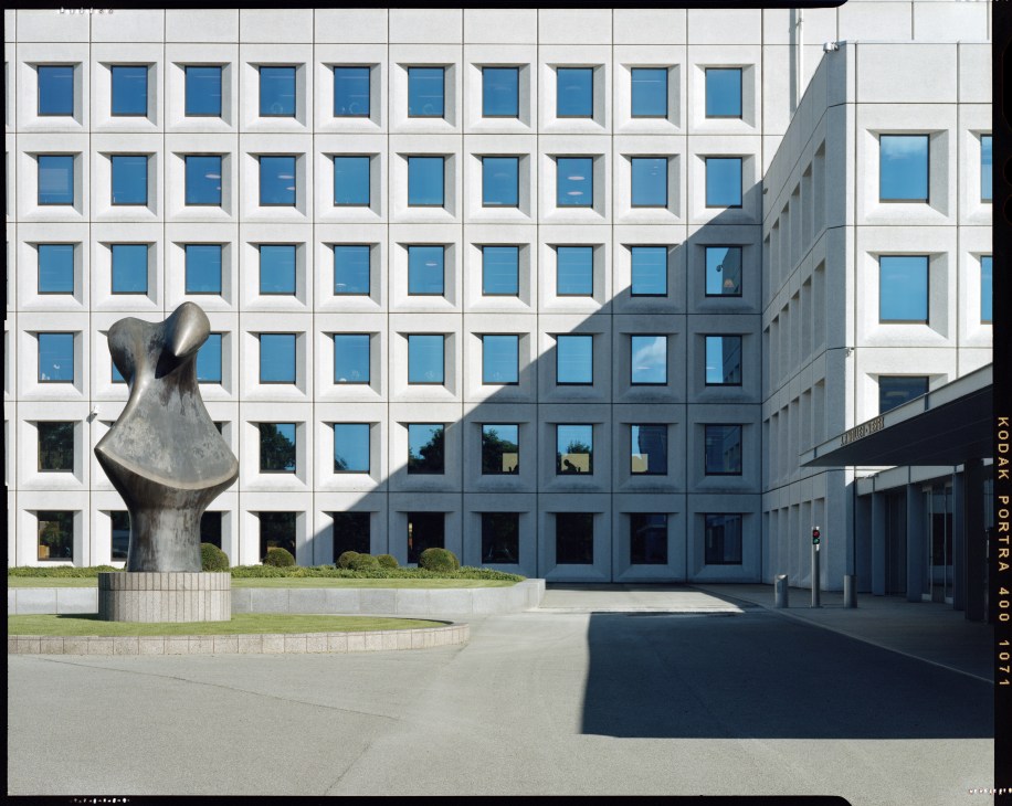 Henry Moore bronze sculpture outside Maersk headquarters with modernist white and blue building facade behind it.