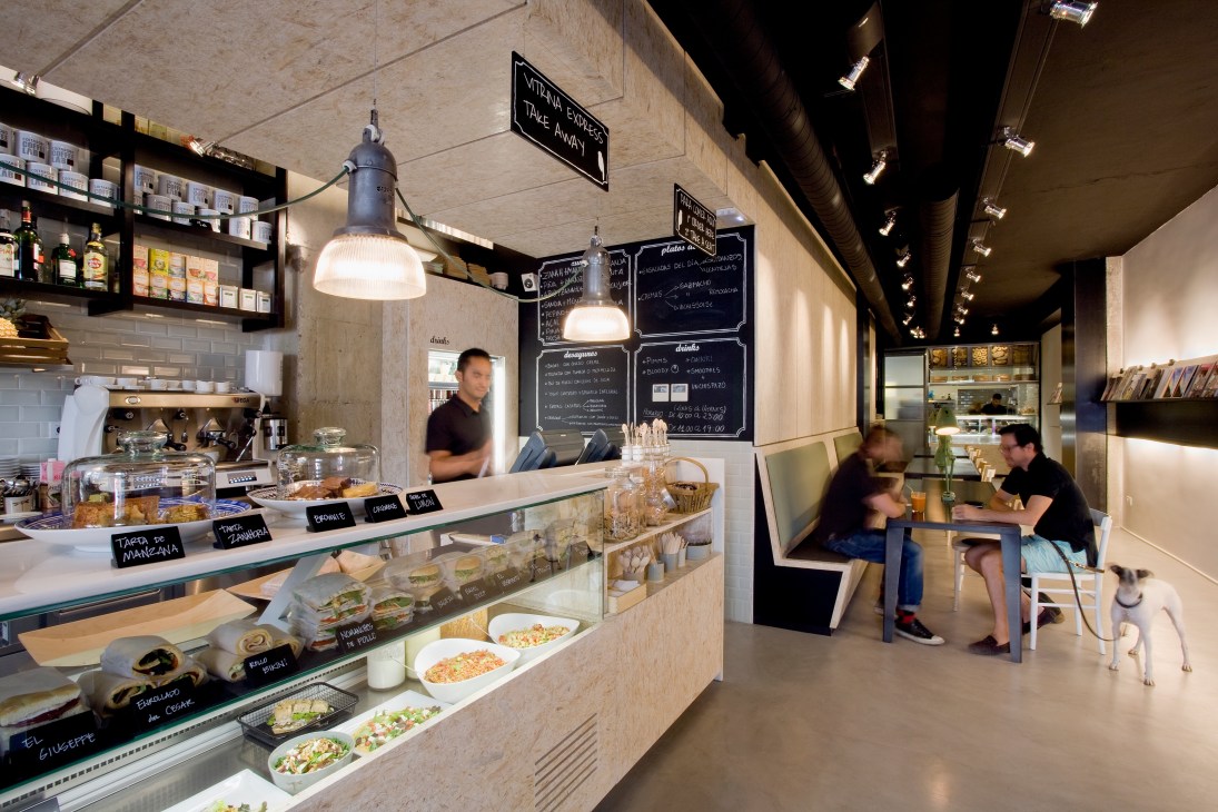 Interior of Magasand cafeteria showing counter with food display, pendant lights, and customers seated at tables.
