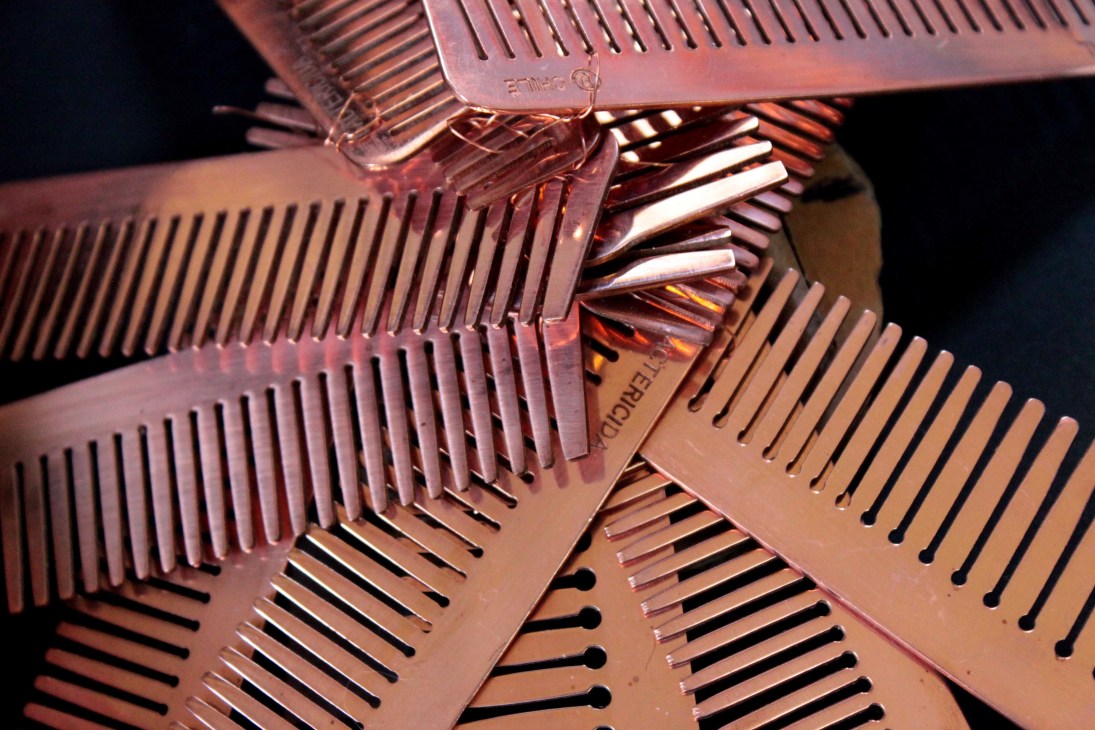 Multiple copper combs arranged together showing their fine teeth and metallic finish.