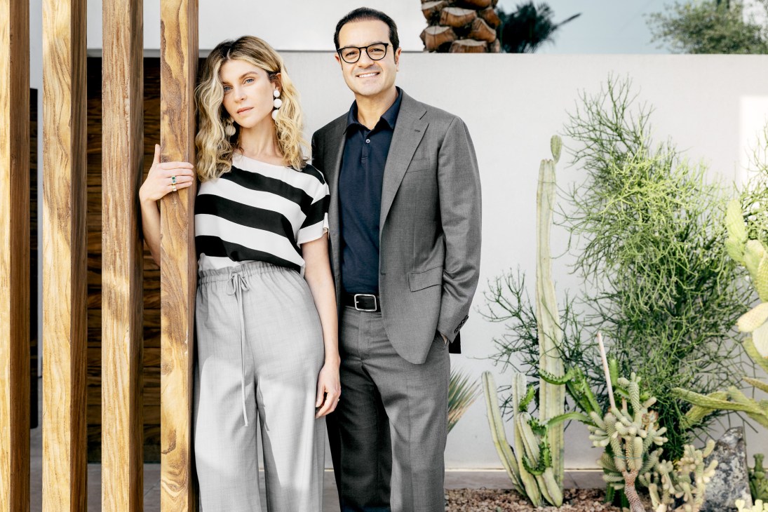 Cherine Magrabi and Amin El-Maghraby stand together in a modern interior with wooden screens and potted plants.