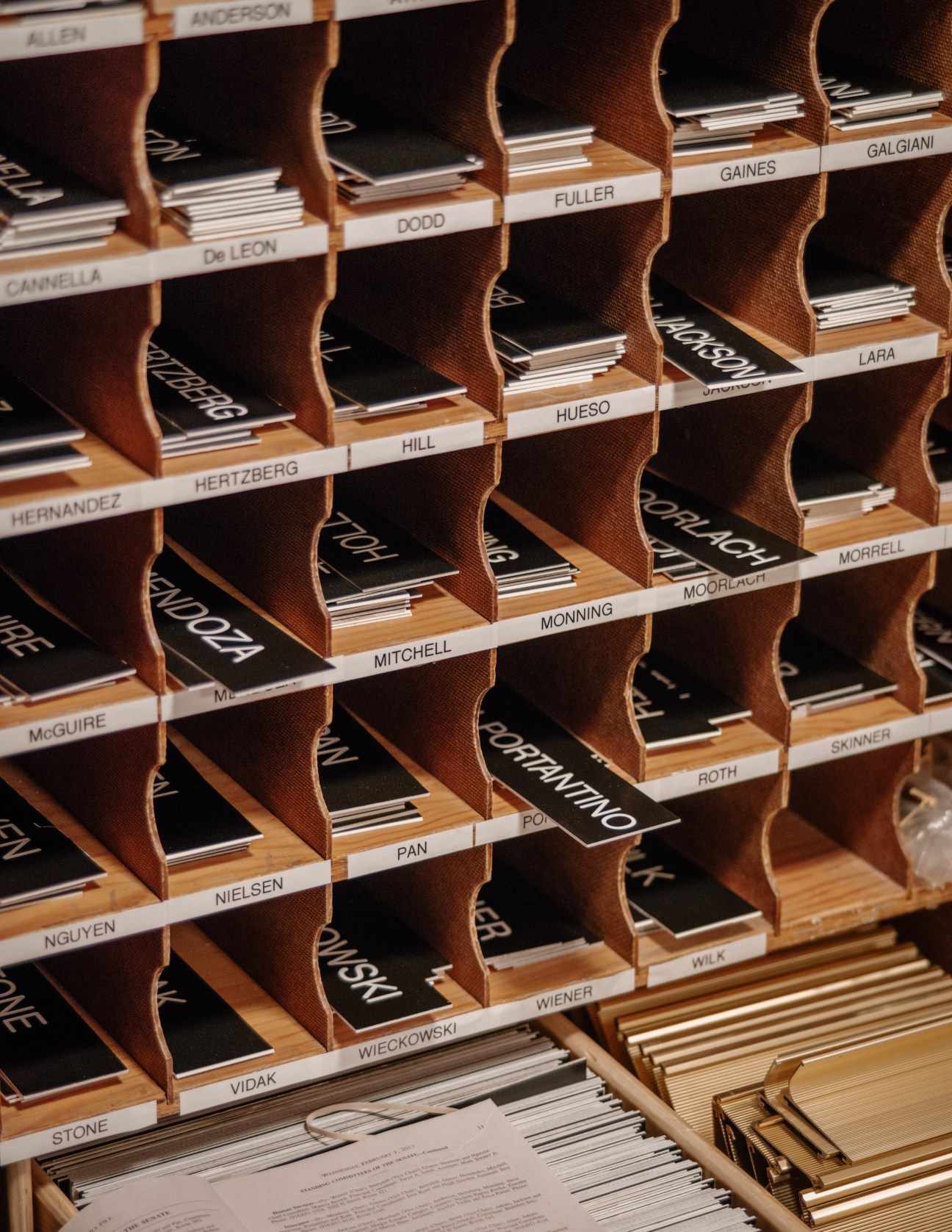 Wooden shelving with labeled dividers displaying name cards for California State Senate members in alphabetical order.