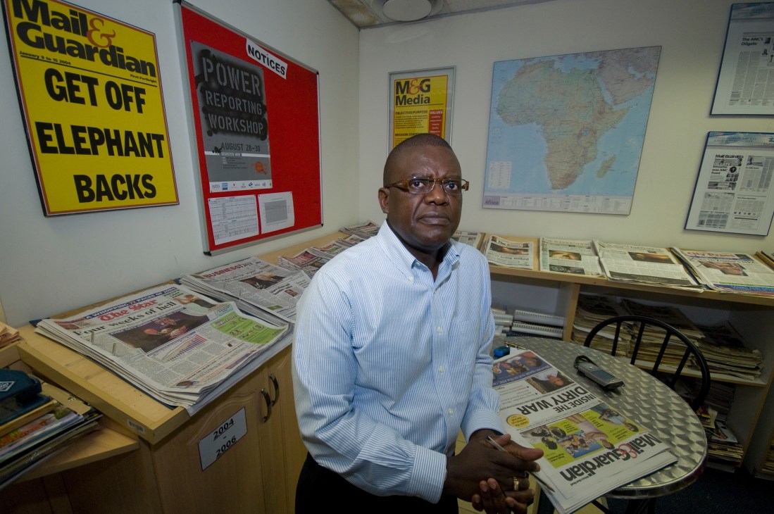 Trevor Ncube stands in the Mail & Guardian newsroom surrounded by newspapers and editorial materials.