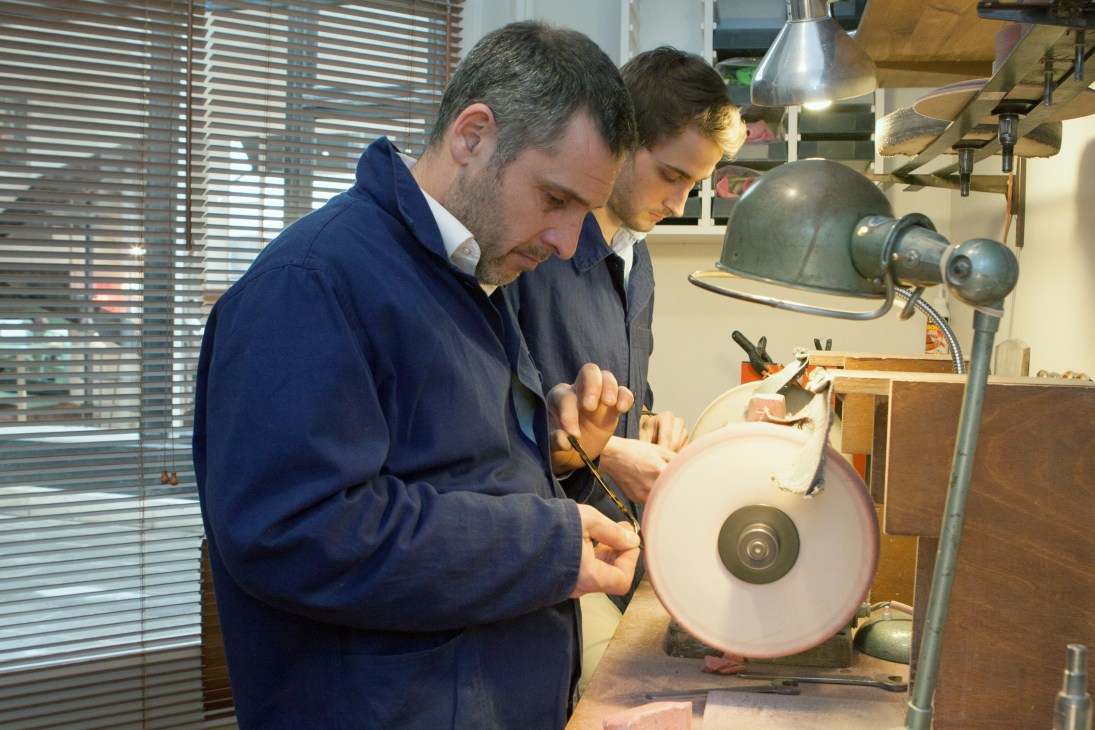 Franck Bonnet and Arnaud Falce polishing eyeglass frames on a grinding wheel in the atelier.