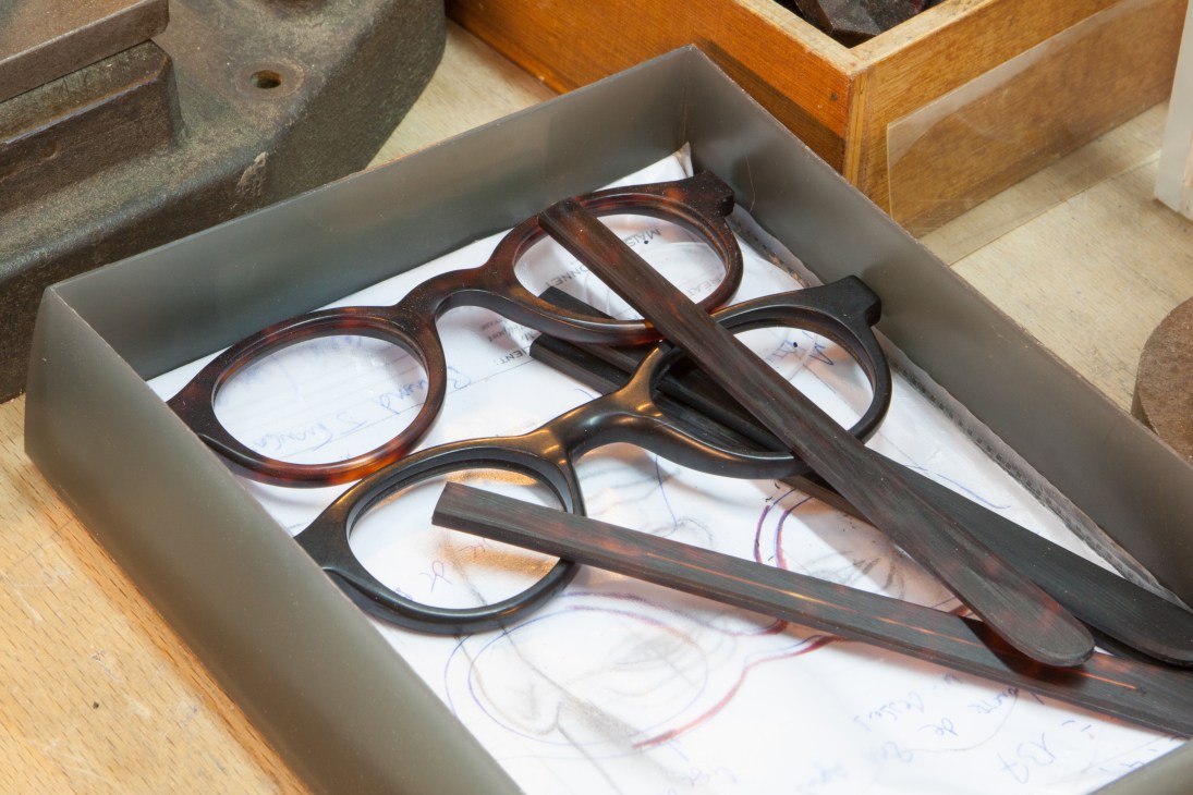 Tortoiseshell eyeglass frames in various stages of completion arranged in a white box.