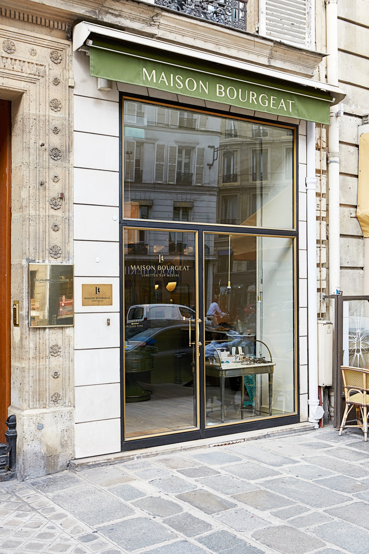 Maison Bourgeat eyewear shop storefront with green awning on Faubourg Saint-Honoré in Paris.