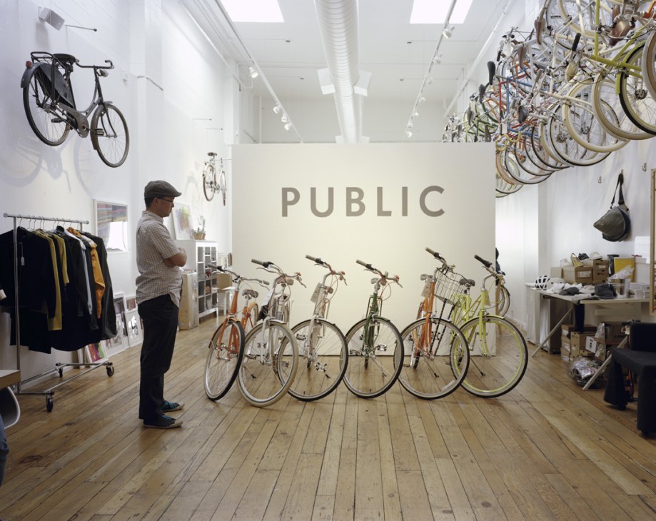 Public Bikes showroom displaying city bikes on wooden floor with wall signage.
