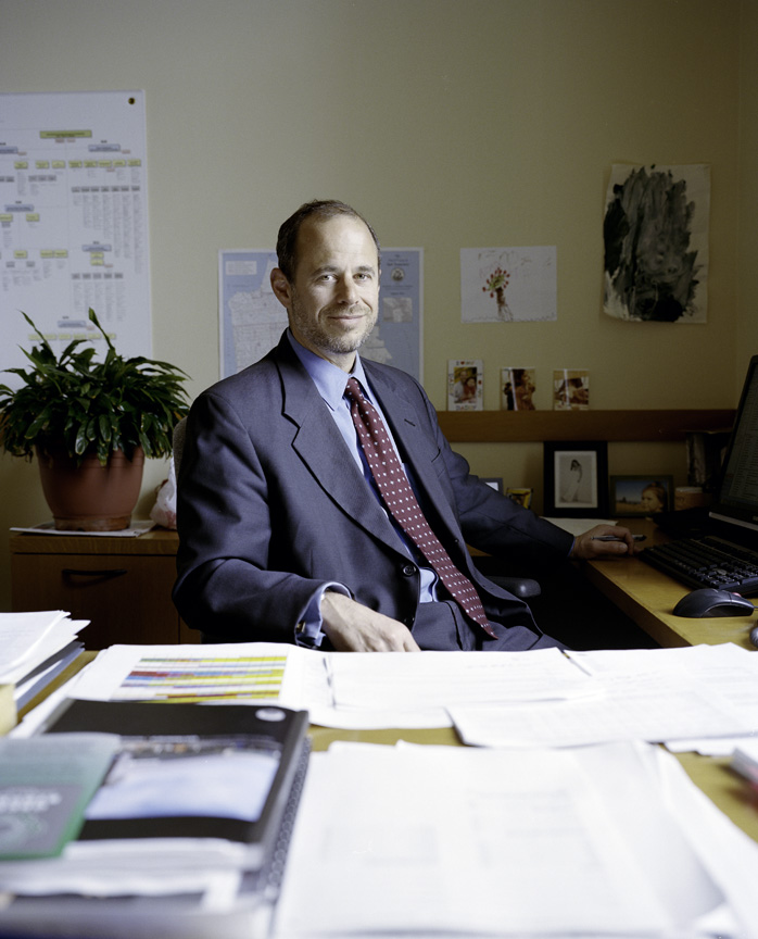 Ed Reiskin, director of public works, sits at his desk in an office with plants and artwork on the walls.