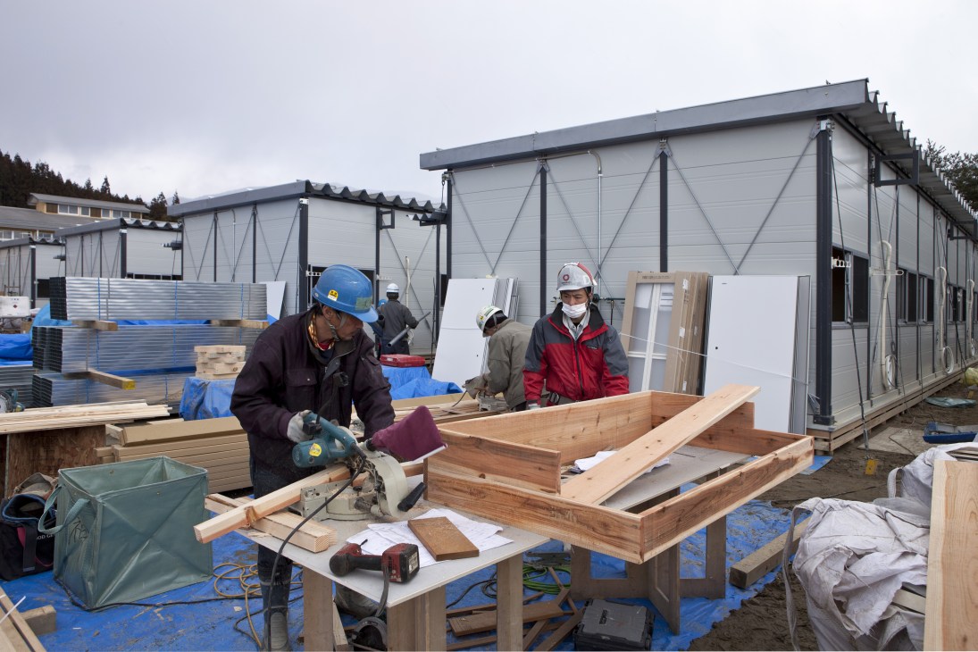 Construction workers assemble wooden components for prefabricated houses at a Daiwa House building site.