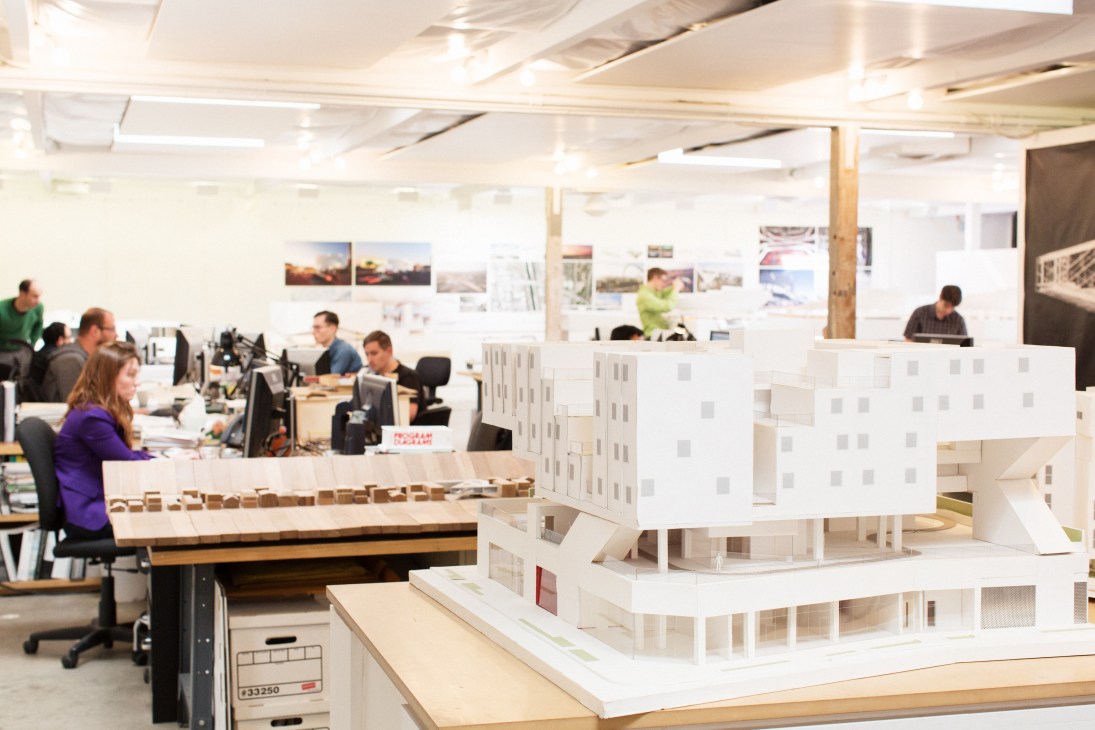 Michael Maltzan's architectural office with staff working at desks and white building models displayed on tables.