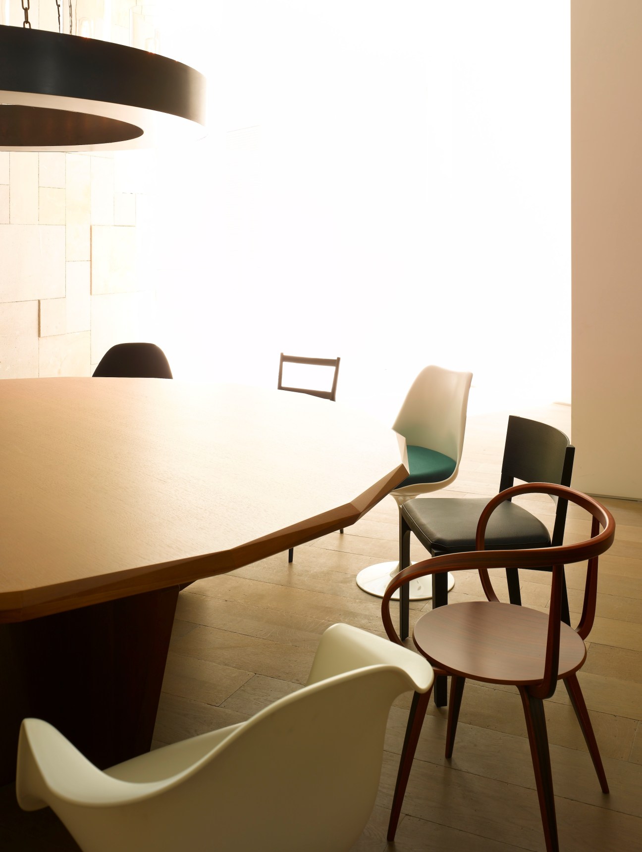 Modern retail or hotel interior with minimalist design, wooden bentwood chairs, white walls, and pendant lighting.