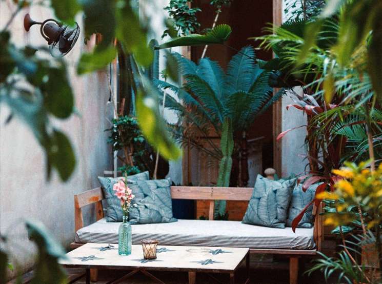 Tropical courtyard seating area with wooden furniture, plants, and string lights at Gardens hotel in Havana