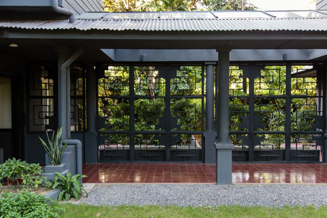 The Henry Hotel hallway with black steel-frame windows and doors overlooking a lush garden courtyard.
