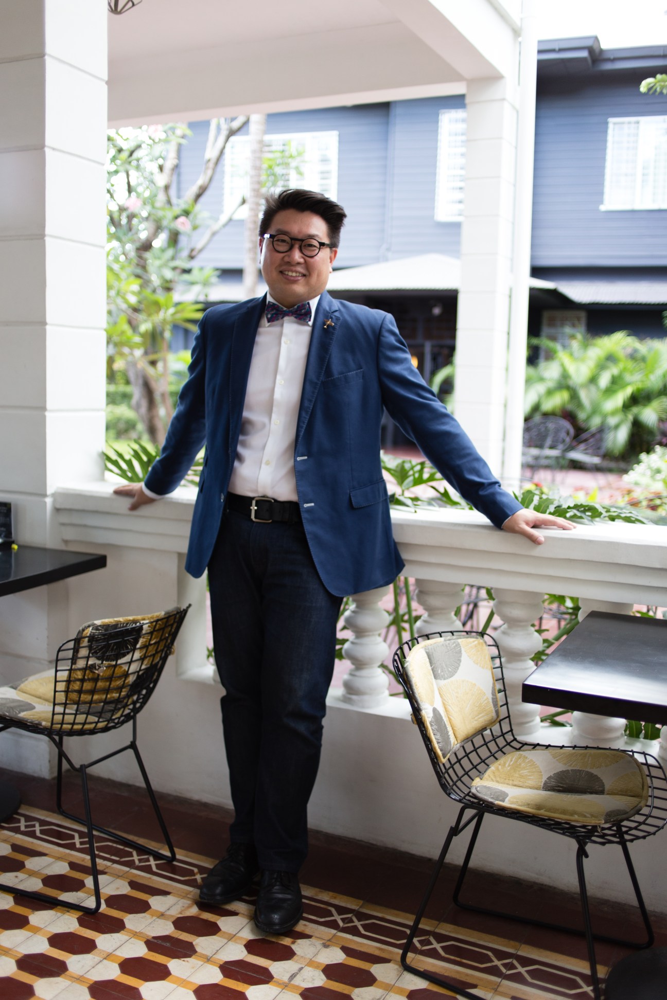 Businessman Hanky Lee stands in an interior space with modern furnishings and windows overlooking a garden.