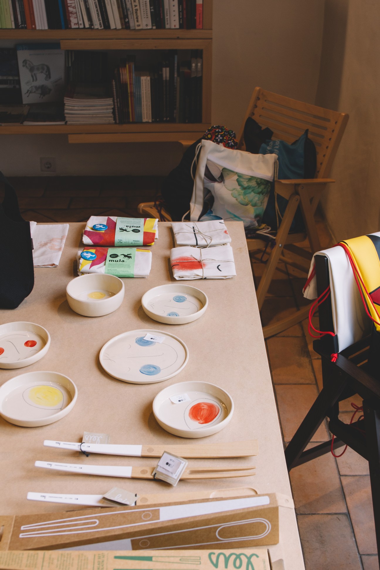 A table displaying handmade ceramics, notebooks, and design products at MAO shop in Ljubljana.