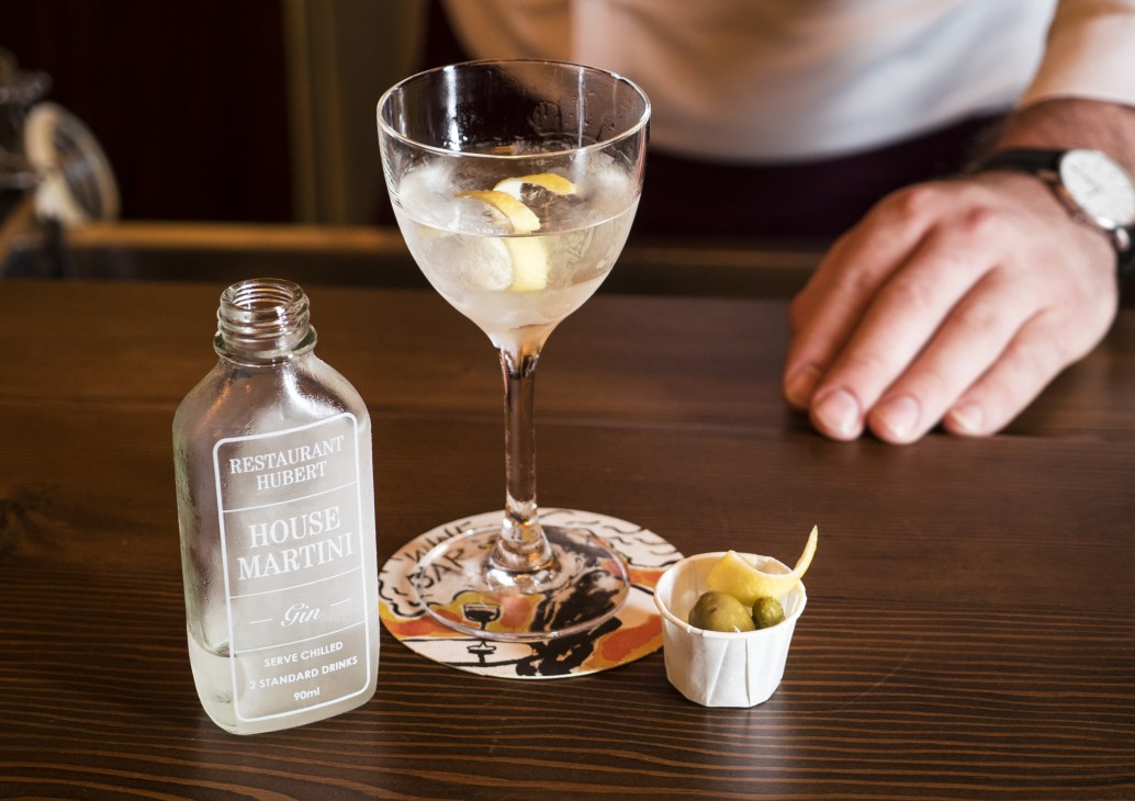 Restaurant Hubert's house martini gin cocktail with olives on a dark wood bar counter.