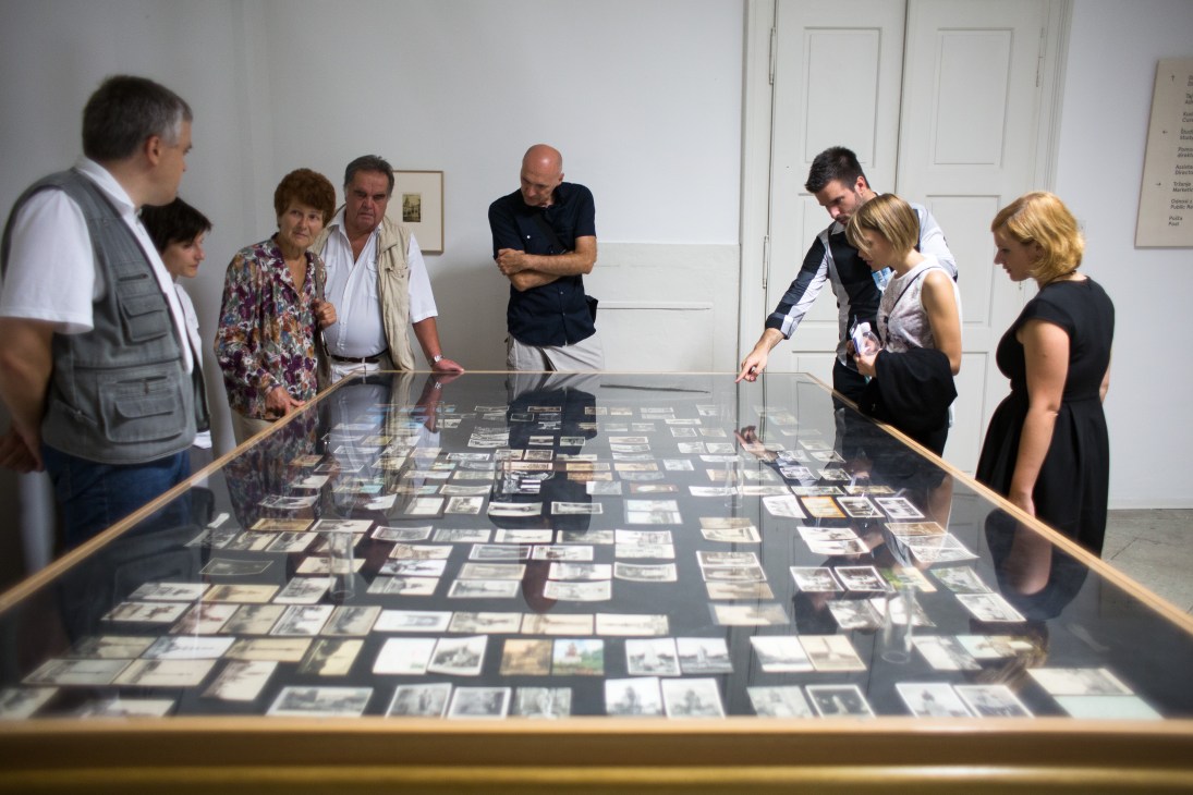 Visitors view Giorgio Andreotta Caló's exhibition of photographs displayed in a glass case.