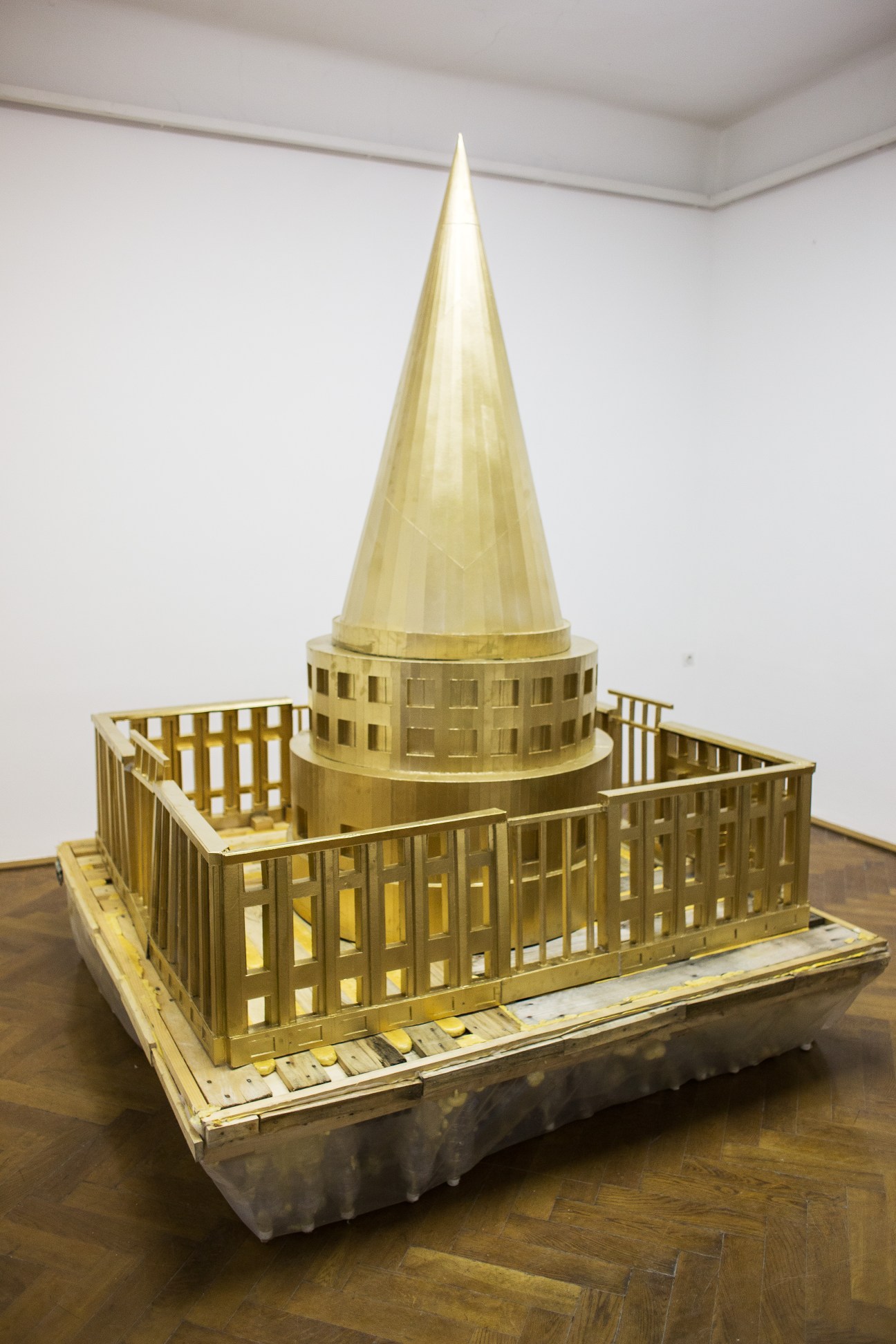 Cardboard architectural model of the Slovenian parliament with golden conical spire and detailed railings.