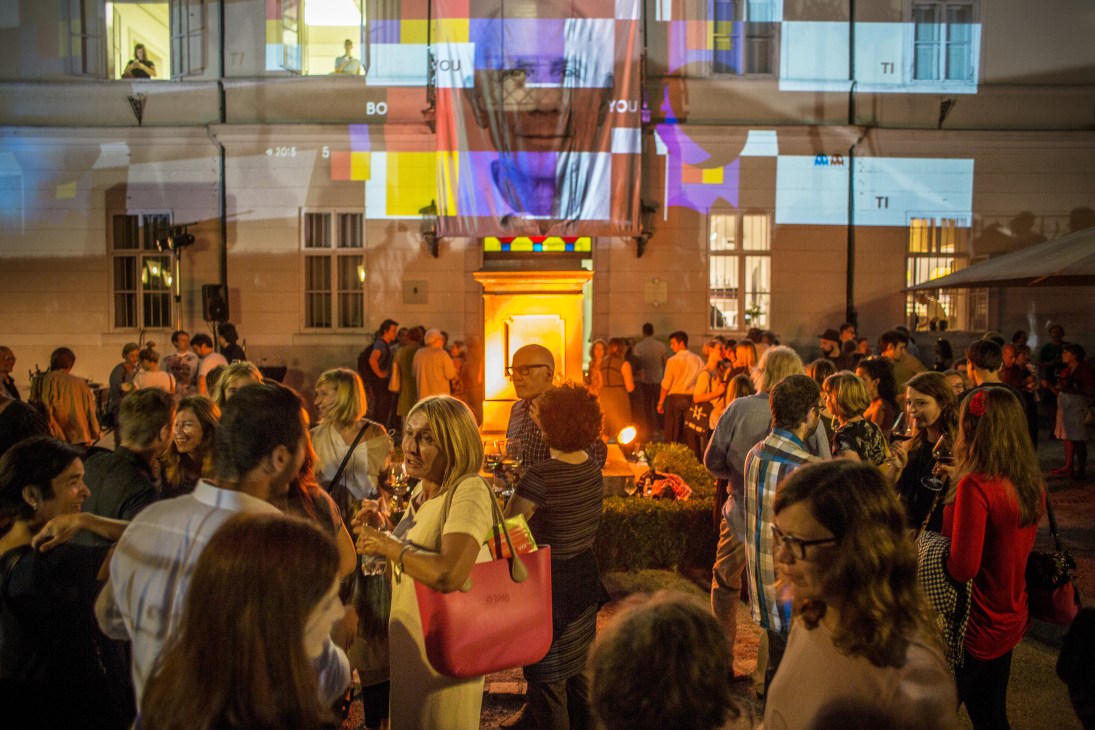 Crowds gather outside the International Centre of Graphic Arts for the biennial opening night, illuminated by colorful projected graphics.