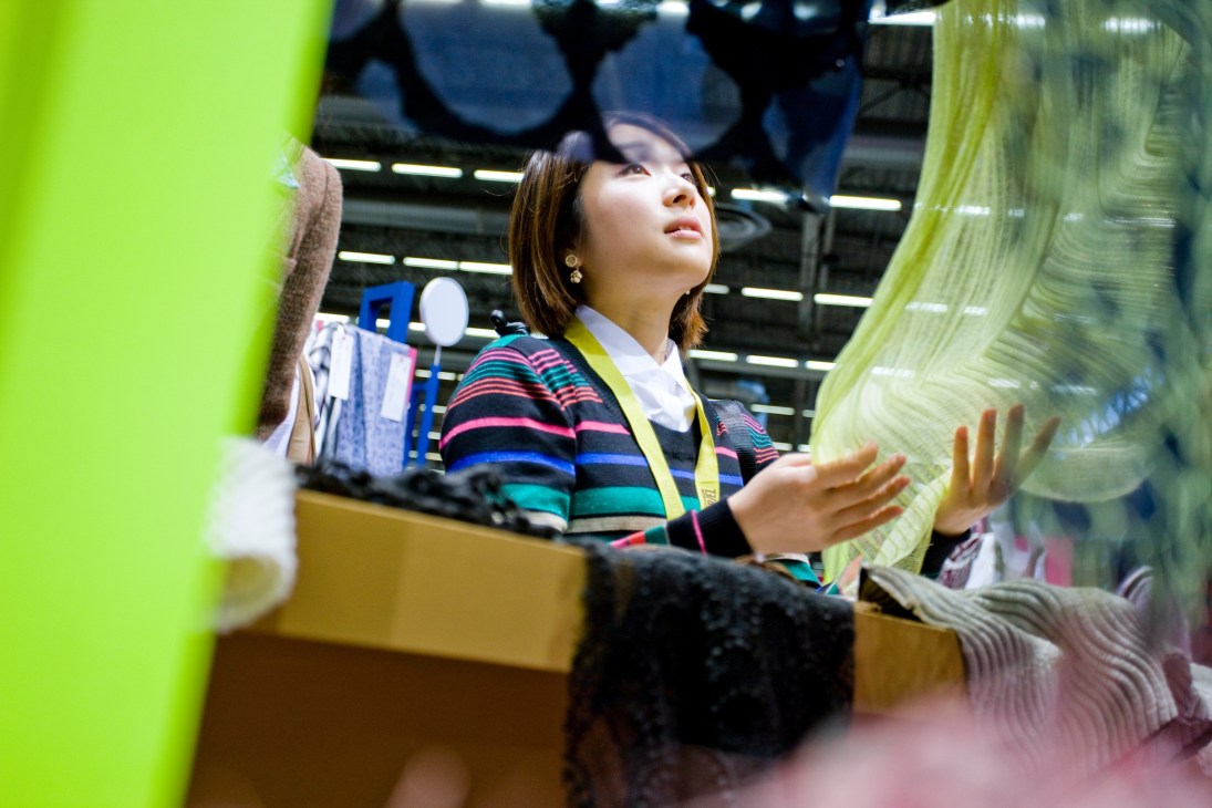 Woman in colorful striped cardigan examining textile samples at a fashion fair.