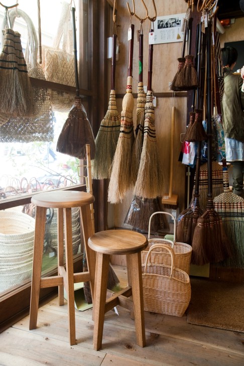 Interior of Matsunoya shop displaying handmade brooms, baskets and wooden stools.
