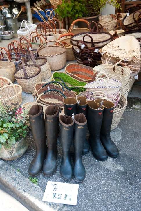 Matsunoya shop display featuring woven baskets and black rubber boots with leather handles.