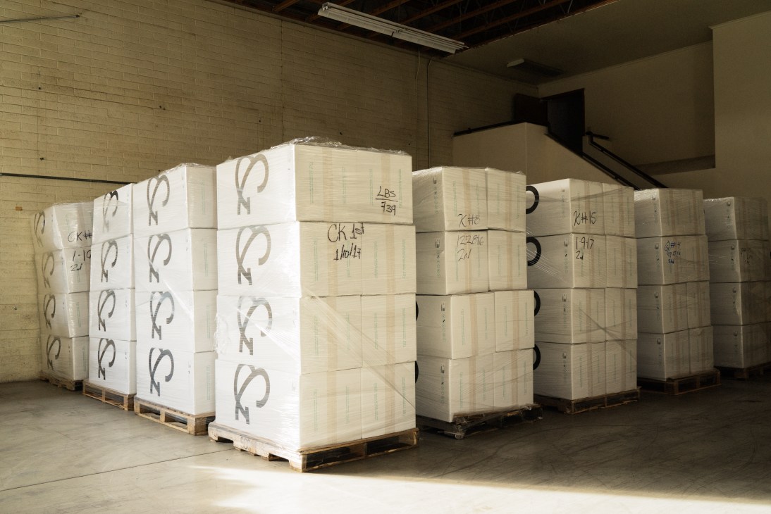 Rows of compressed and vacuum-sealed mattresses stacked in boxes at Tuft & Needle's Phoenix warehouse.