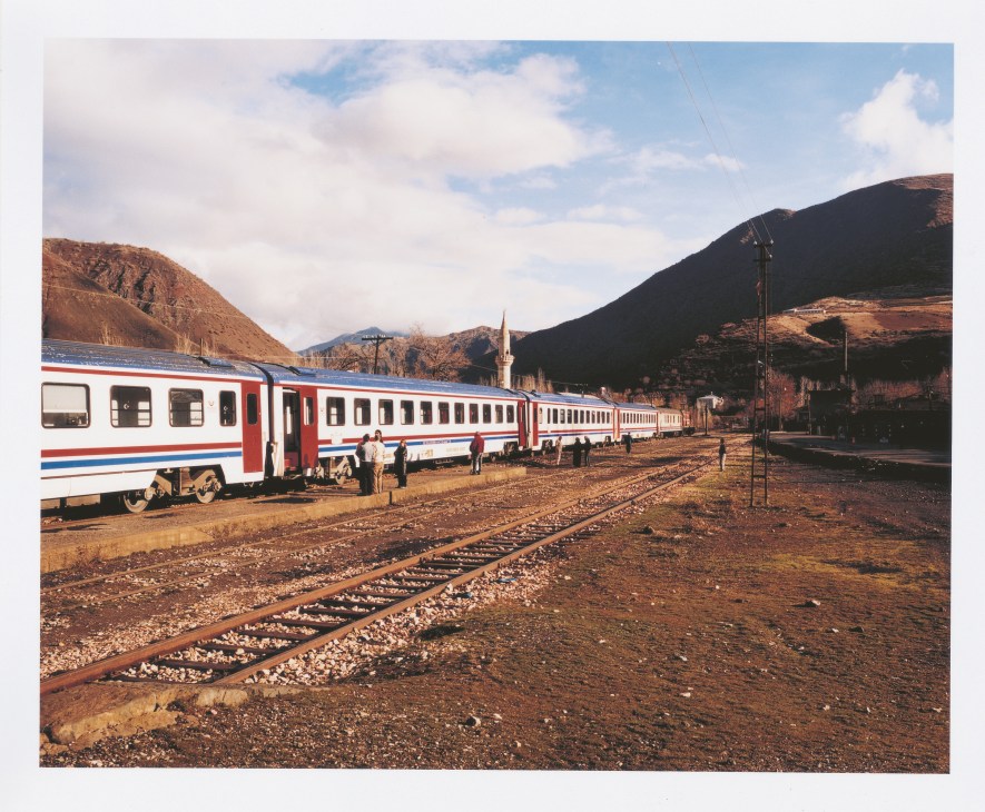 TransAsya Express train stopped at Turkish military checkpoint in mountainous terrain with armed guards nearby.