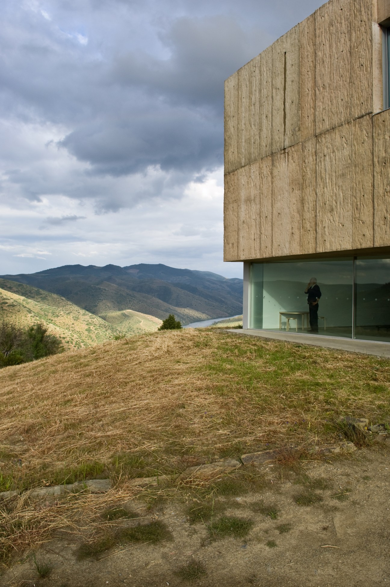 Modern museum building with stone facade and glass windows set on a hillside overlooking a valley in Portugal.