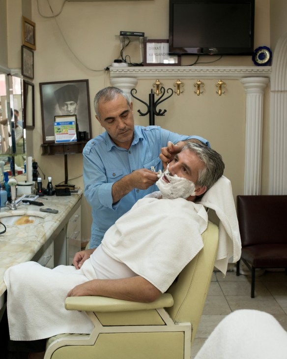Master barber Huseyin Akbay shaving a customer with a straight razor at Cornedor barbershop in Istanbul.
