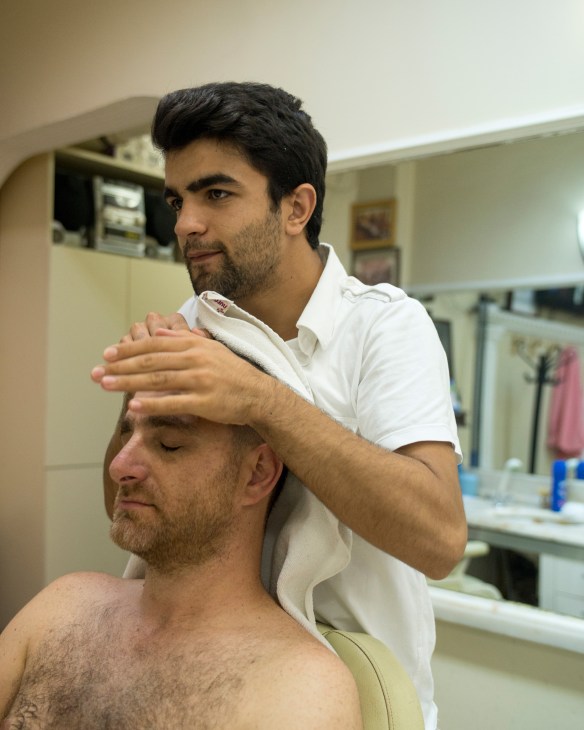 Apprentice Aydin Simsek performing a traditional head-and-shoulder massage on a customer at Cornedor barbershop in Istanbul.