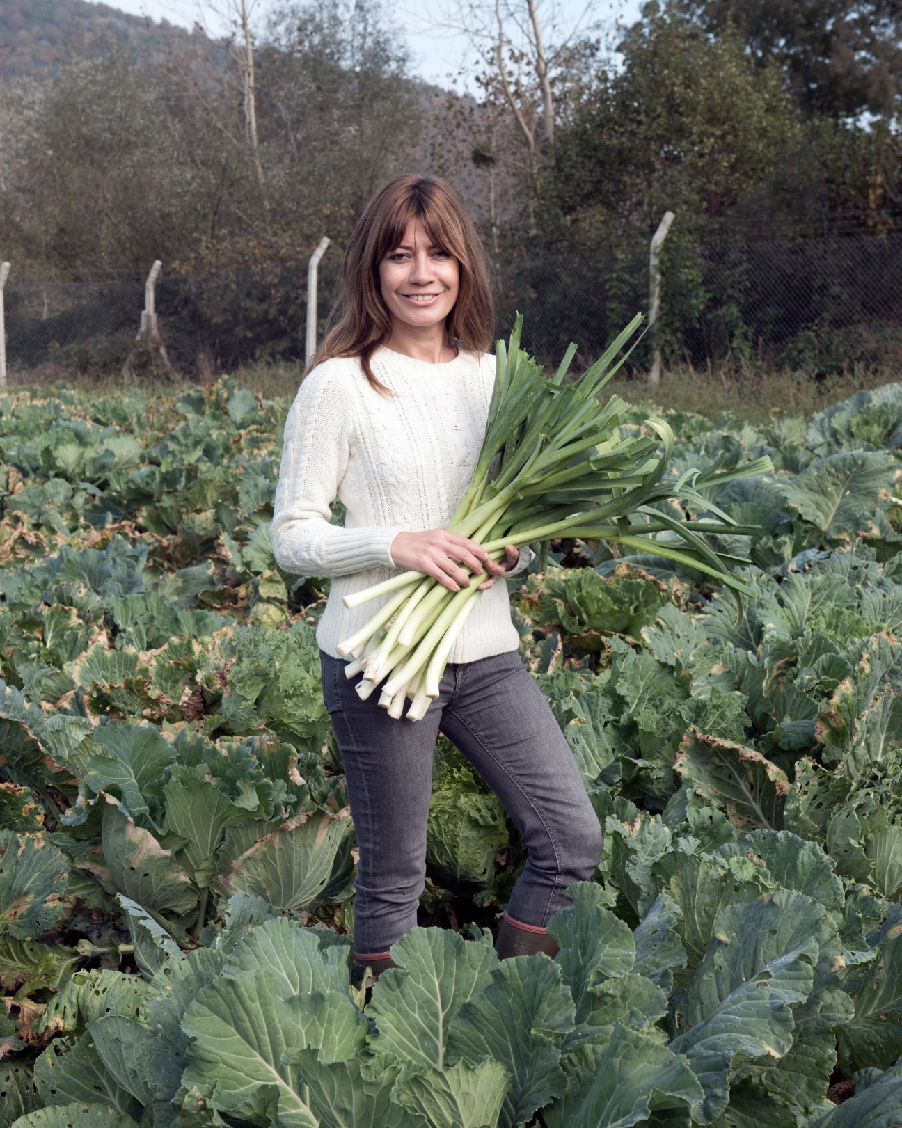 Woman holding harvested leeks in a vegetable field at Komsukoy farm.