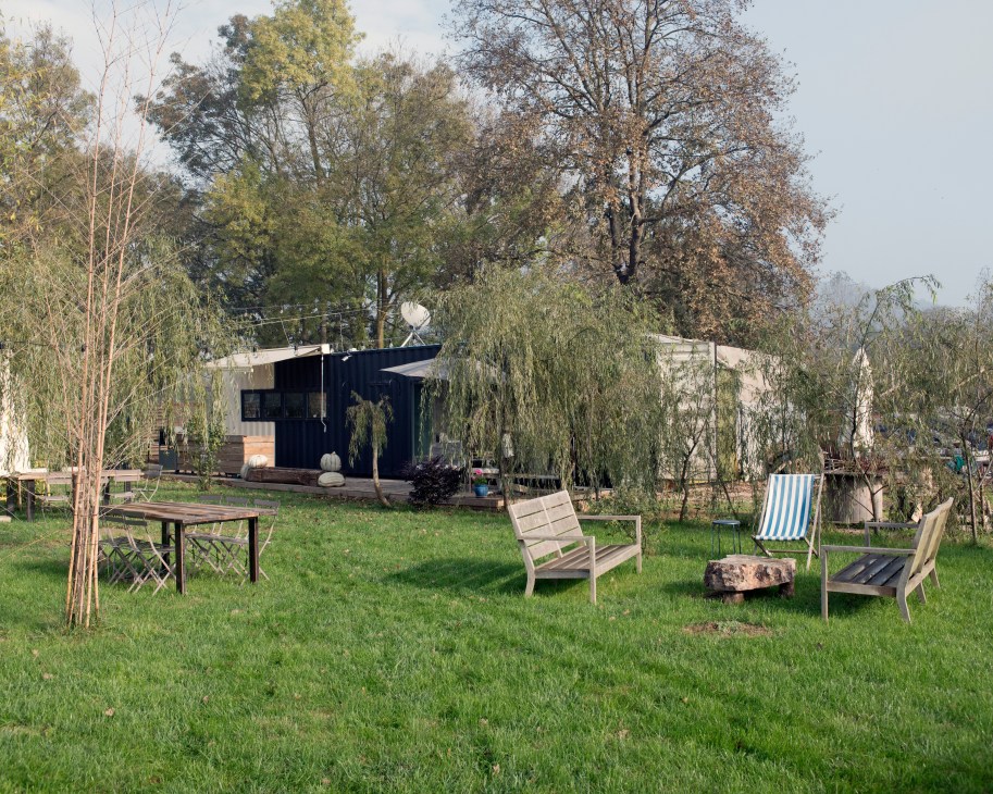 Black cabin structure surrounded by lawn chairs and trees at Komsukoy farm in Turkey.