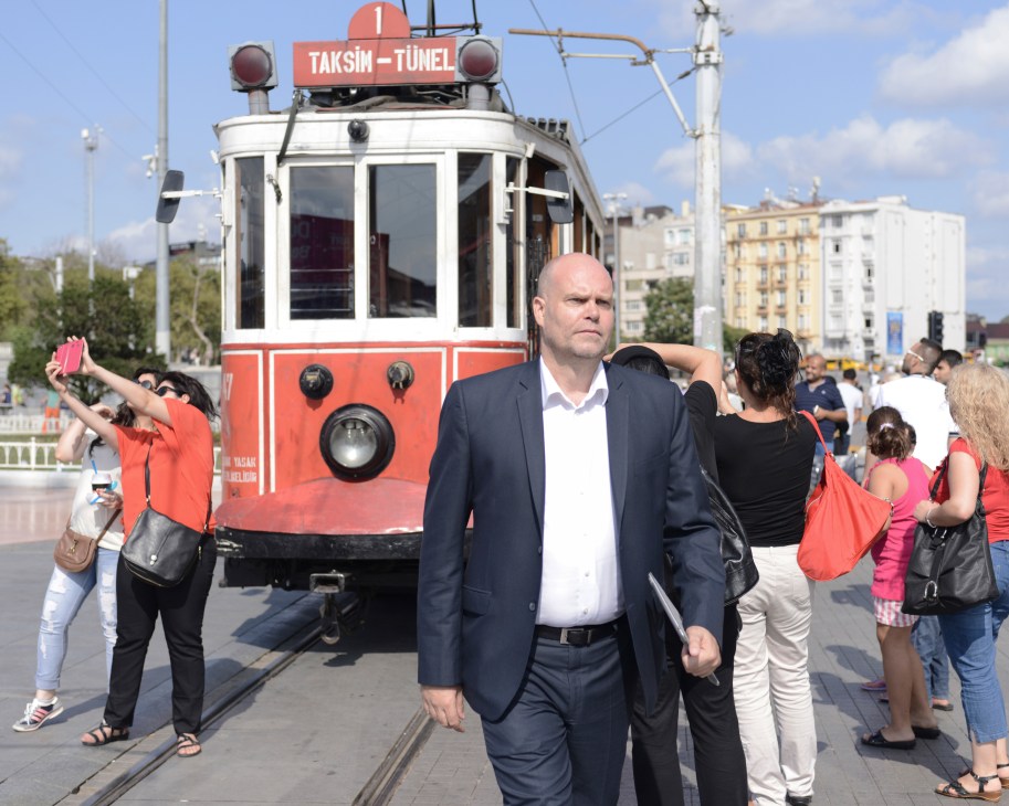 Ivan Nielsen, Danish special envoy to the Syrian opposition, walks past a red Istanbul tram in Taksim Square.