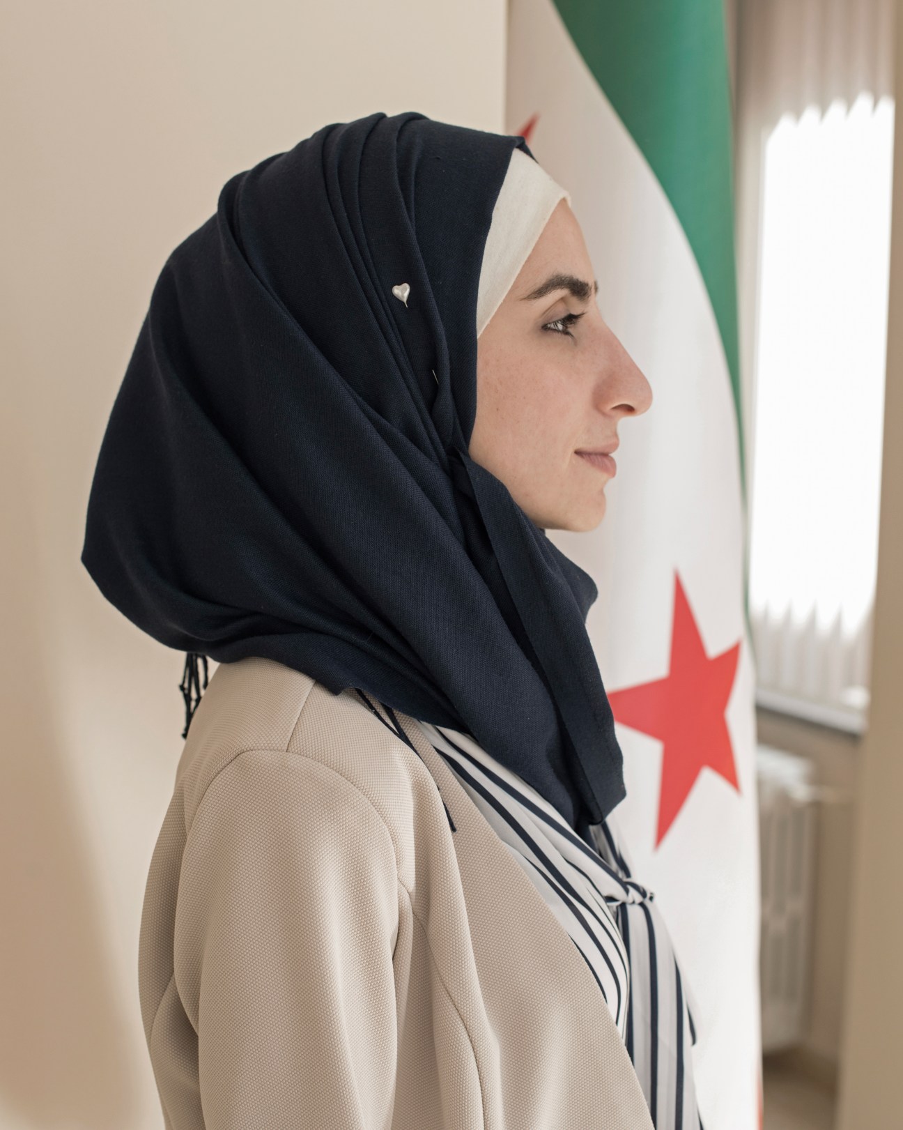 Noura Al Amir, Etilaf vice-president, wearing a dark hijab in profile against a Syrian flag