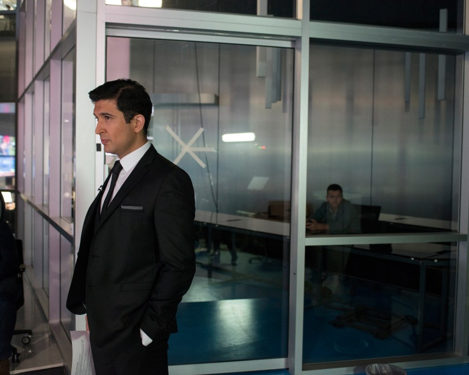 Imran Garda in a black suit and tie standing in the TRT World studio corridor.