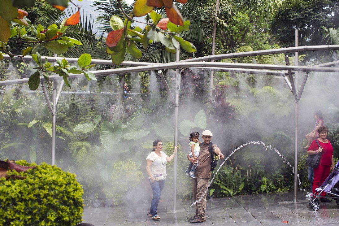 Families enjoy mist fountains and tropical plants at Parque Explora museum in Medellín.