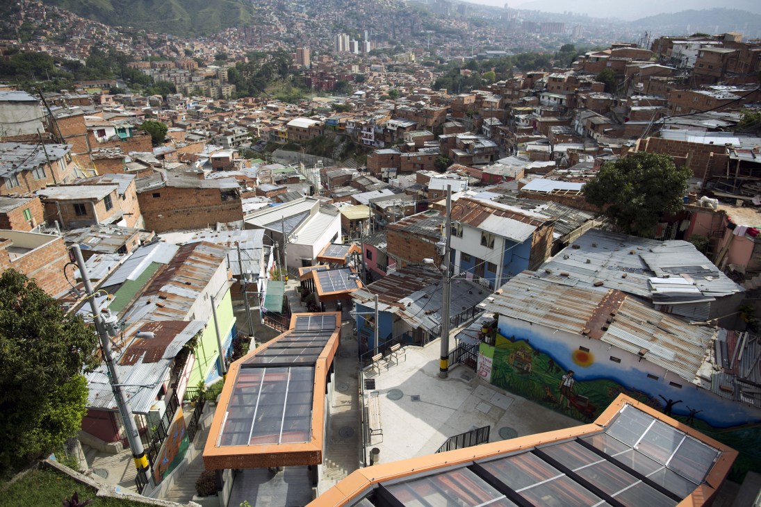 Aerial view of Medellín slum with solar-paneled rooftops and escalators connecting hillside buildings.