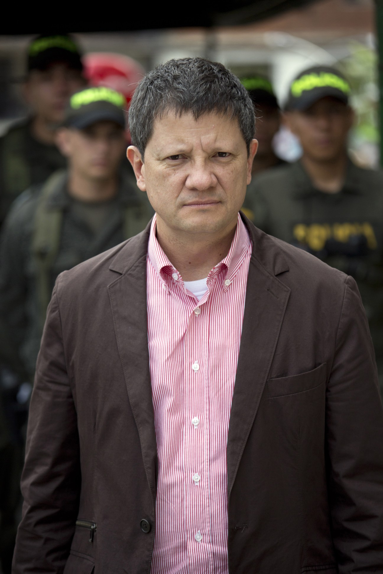 Vice-mayor for security Luis Suárez standing outdoors with armed personnel in the background.
