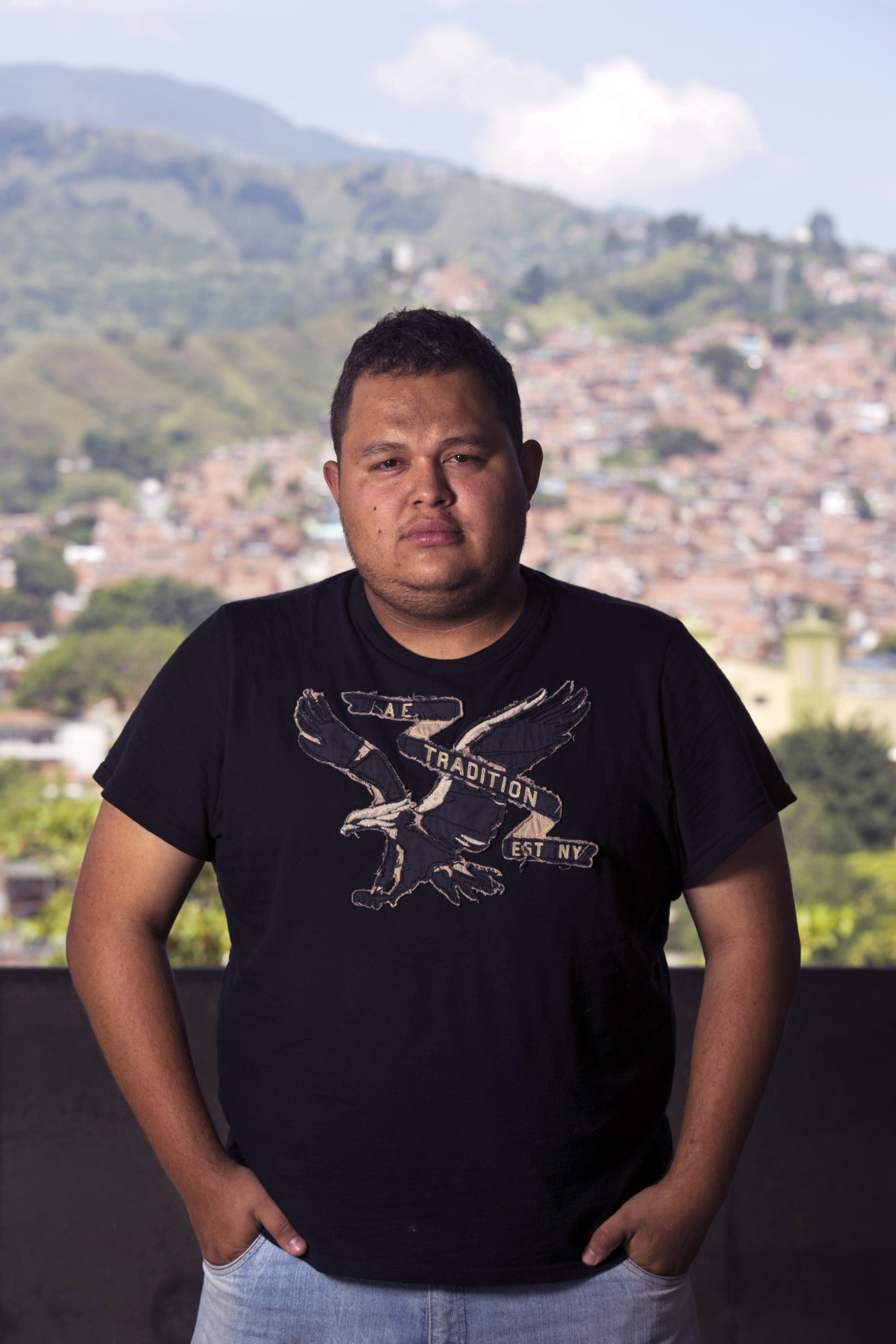 Jeihhco, a rapper and cultural innovator, poses against a hillside view of Medellín's sprawling neighborhoods.