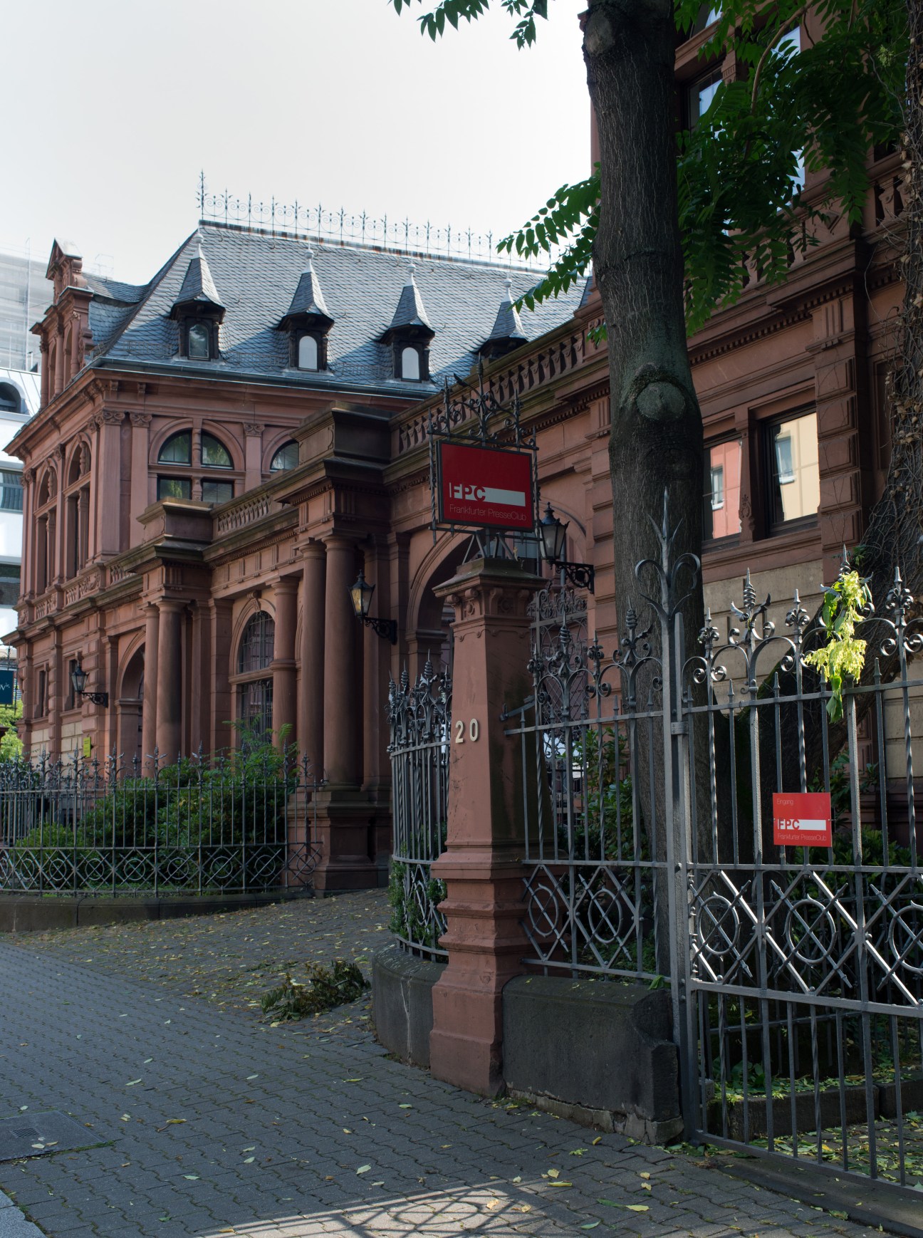 Red brick building with mansard roof and ornate ironwork gate, marked with EPO signage.