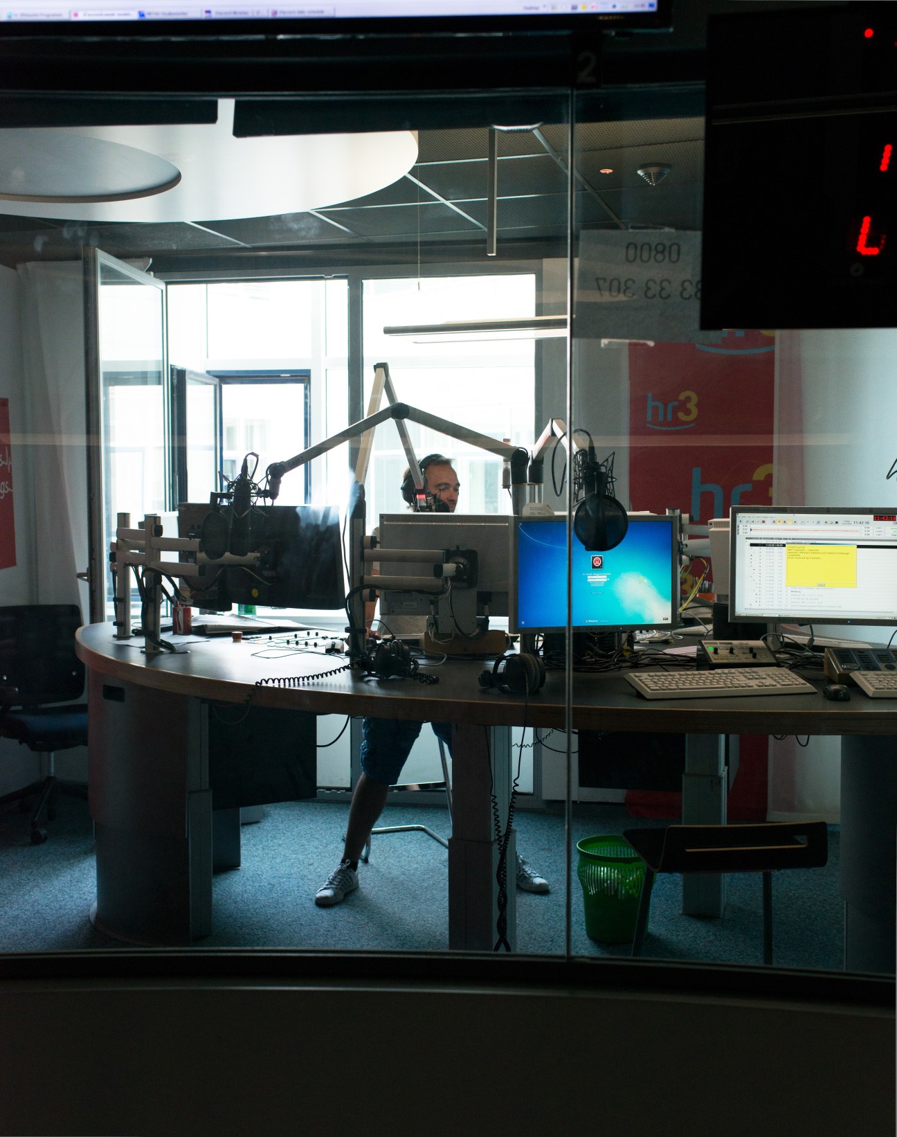 Radio DJ Mirko Förster sits at a broadcasting desk with microphone and equipment in an HR3 studio.