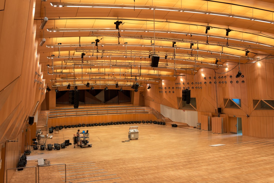 Large wooden concert studio with professional lighting rig and acoustic panels overhead.