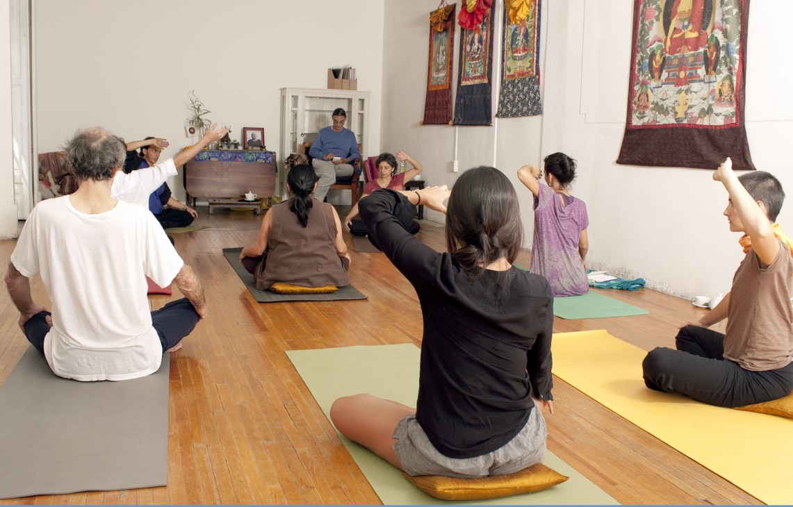 Yoga class at Casa Drölma with multiple participants on colored mats following an instructor.